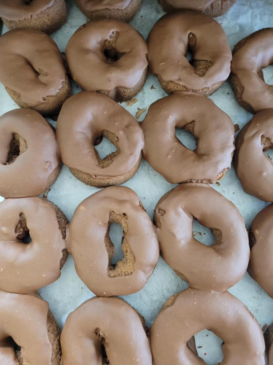 Trays of iced ring donuts at World's Fair Donuts, laid out in rows on a pale green tray